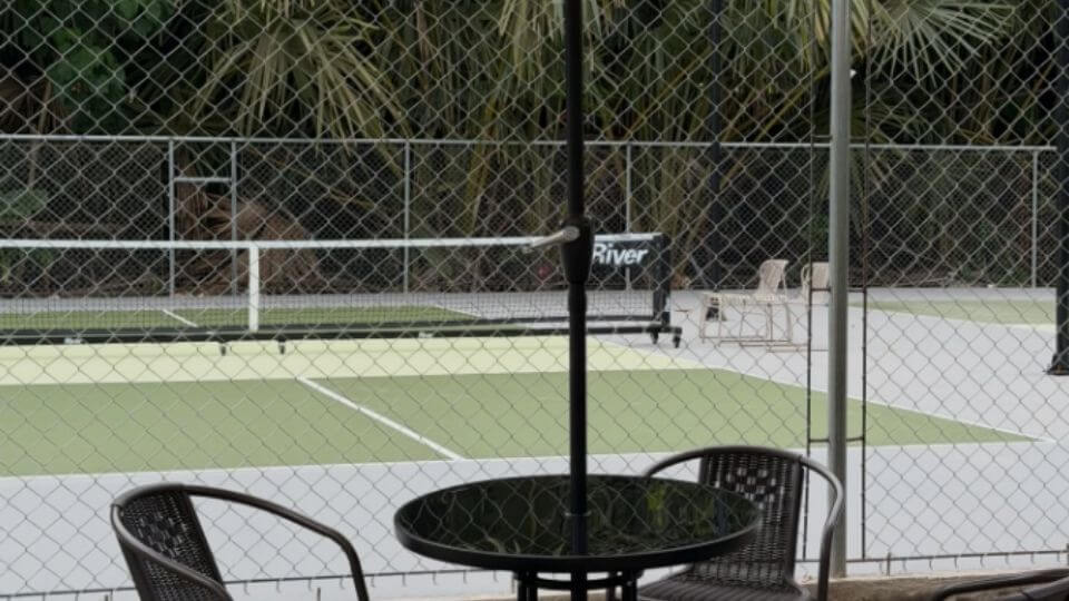 Kahoy Pickleball court - shot through a wire wall and table and chairs